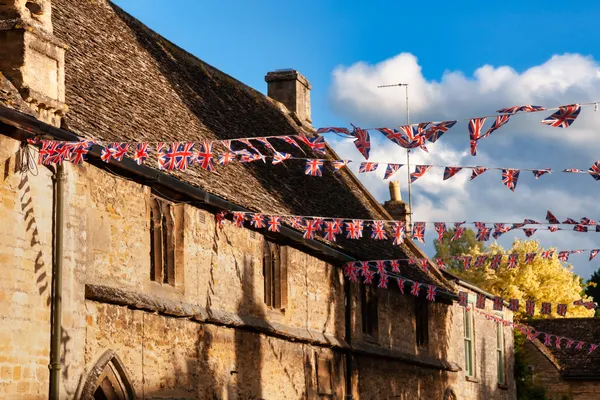 The roof and top floor of an old-fashioned manor house decorated with Union Jack bunting